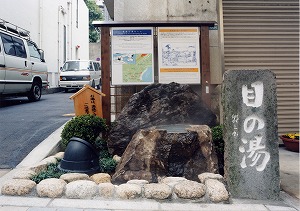 写真：道路脇にある目の湯。岩が置かれ看板が立てられている
